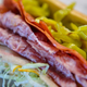 close-up shot of an Italian sub sandwich with meat, lettuce, pickled peppers, and vinegar